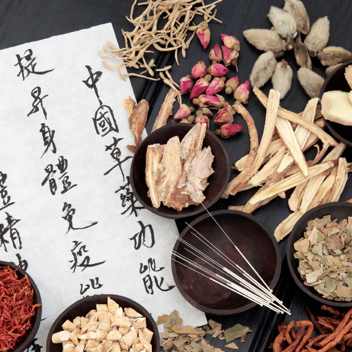 An array of Chinese herbs, acupuncture needles, and a list written in Mandarin or Cantonese.
