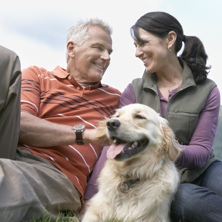 A smiling middle-aged couple with their dog.