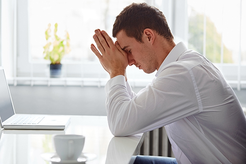 A young office worker holding his forehead because he's stressed.