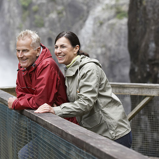 An older couple wearing rain coats and enjoying a hike.