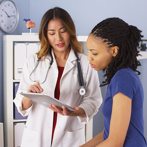 A doctor and a young woman review the woman's medical chart.